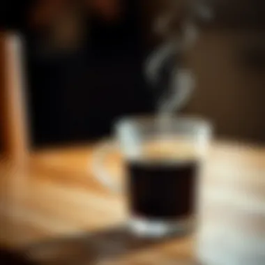 A close-up of a steaming cup of black filter coffee on a wooden table.